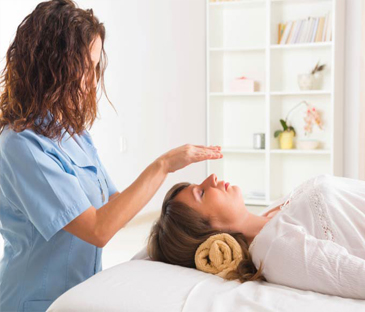 Terapeuta aplicando Reiki em paciente deitada